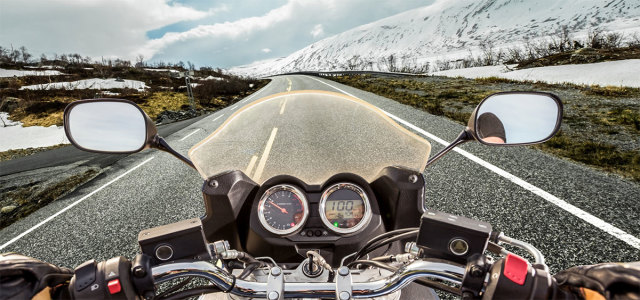 Point of view photograph of a motorcyclists driving down a long empty highway